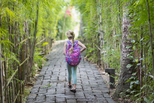 Caucasian girl walking on stone path among bamboo trees