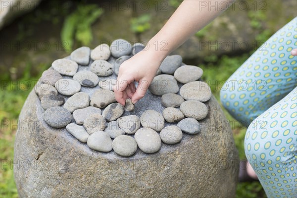 Caucasian girl arranging stones on boulder