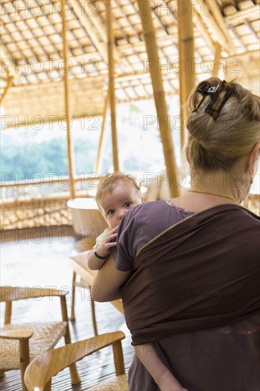 Caucasian mother carrying baby boy on patio