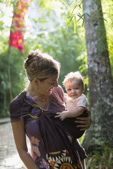 Caucasian mother carrying baby in rainforest