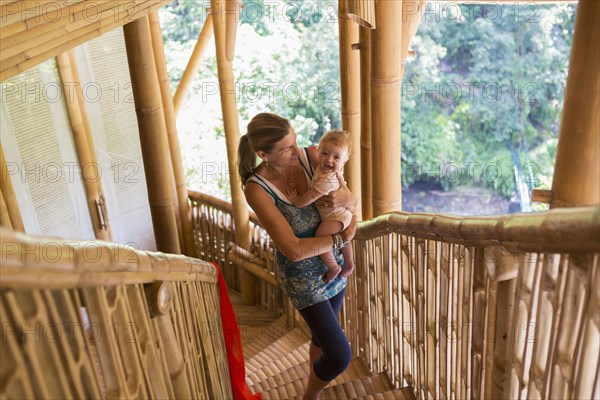 Caucasian mother carrying baby up stairs