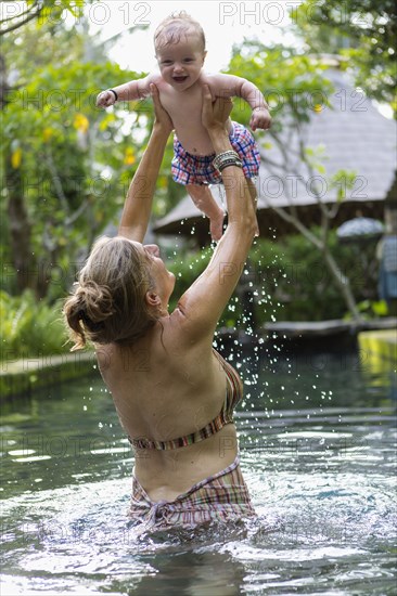 Caucasian mother and baby playing in pool
