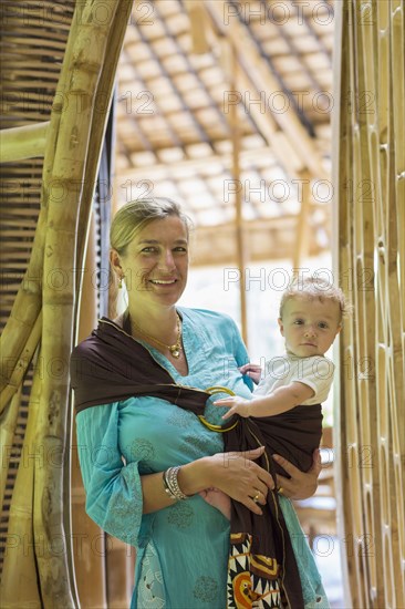 Caucasian mother holding baby in bamboo doorway