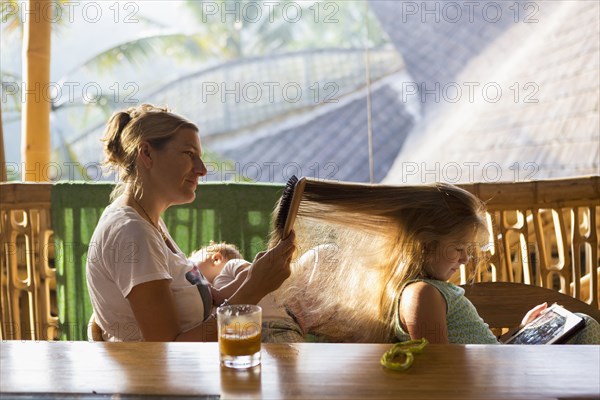 Caucasian mother brushing daughter's hair on patio