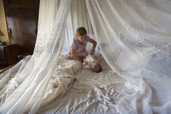 Caucasian girl and baby boy playing in bed