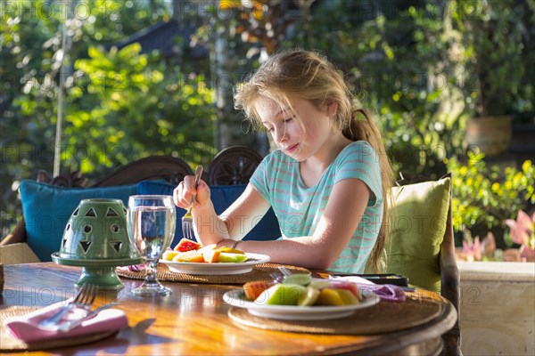 Caucasian girl eating breakfast at table