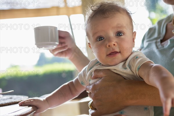 Caucasian mother holding baby at breakfast