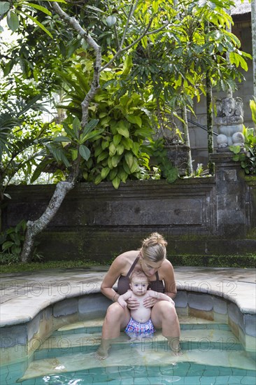 Caucasian mother and baby relaxing in swimming pool