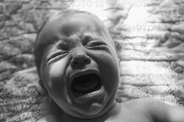 Caucasian baby crying on bed