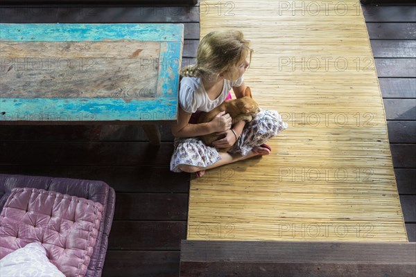 Caucasian girl holding cat on patio