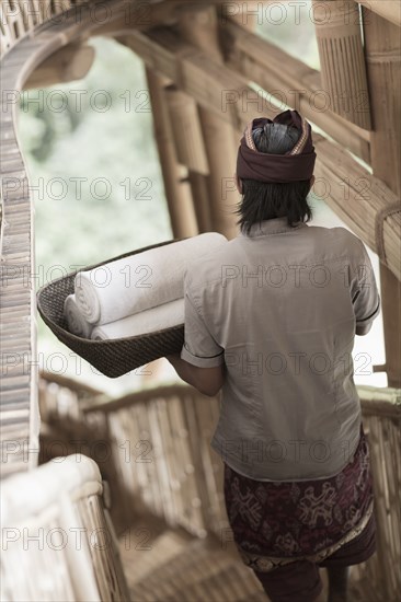 Balinese man carrying rolled towels in hotel