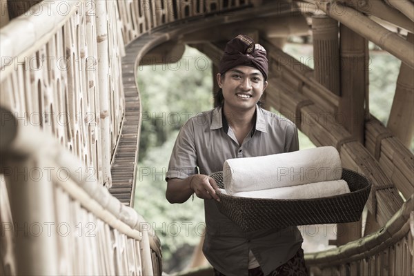 Balinese man carrying rolled towels in hotel