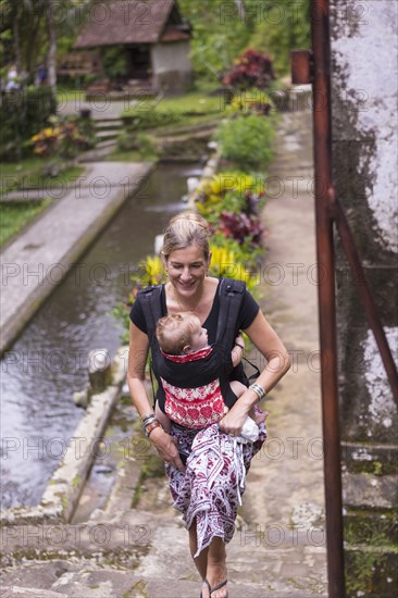 Caucasian mother carrying baby on stone walkway