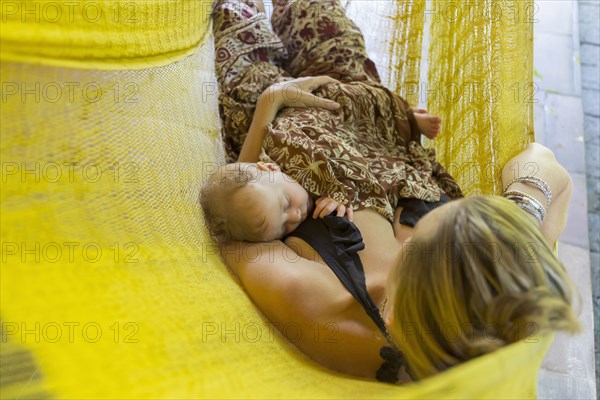 Caucasian mother and baby relaxing in hammock