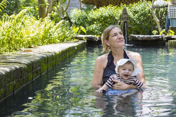 Caucasian mother and baby relaxing in swimming pool