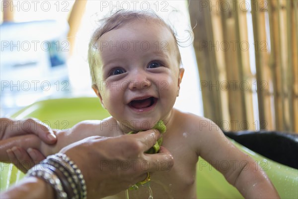 Caucasian mother washing baby in plastic tub