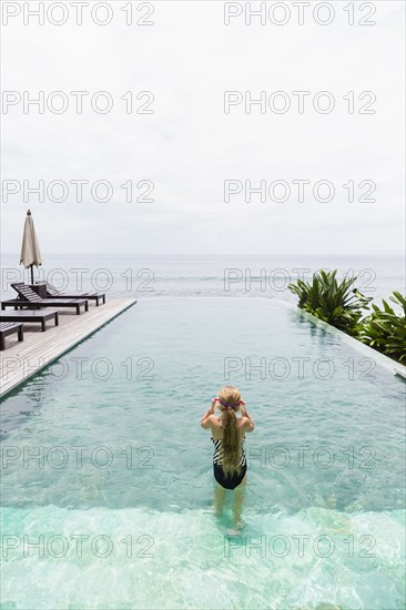 Caucasian girl swimming in infinity pool