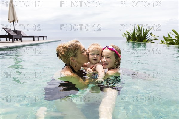 Caucasian family relaxing in infinity pool