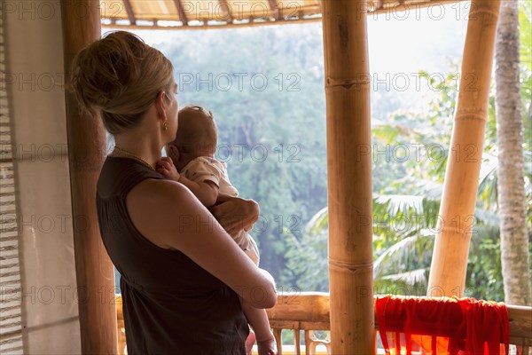 Caucasian mother holding baby on balcony