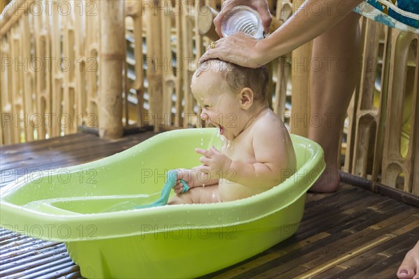 Caucasian baby having bath in tub
