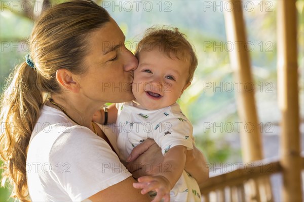 Caucasian mother kissing baby's cheek