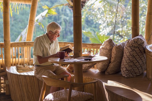 Senior Caucasian man reading at patio table