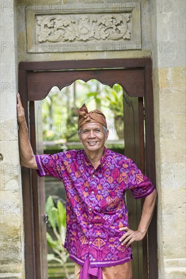 Balinese worker smiling in wood archway