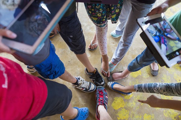 Children taking pictures of shoes with digital tablets