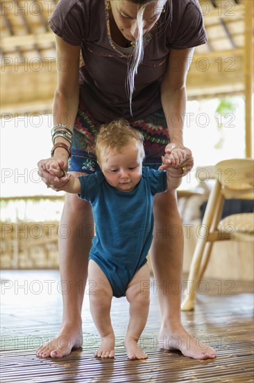 Caucasian mother helping baby walk