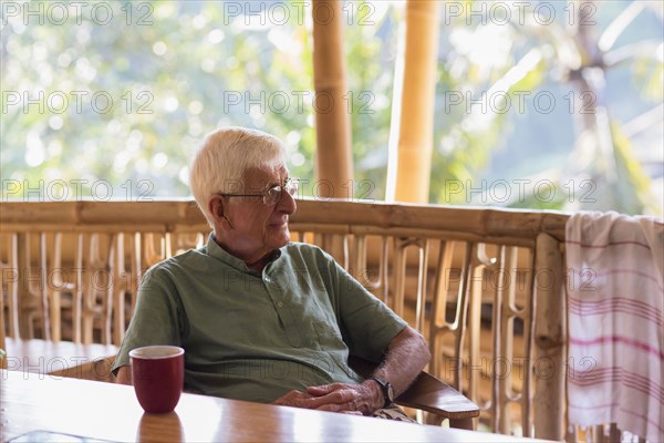 Caucasian man having cup of coffee in treehouse