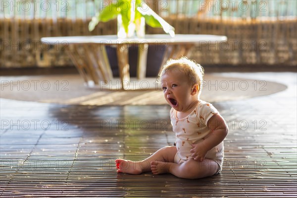 Caucasian baby yawning on floor