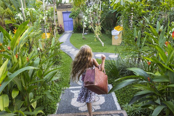 Caucasian girl carrying purse on stone backyard steps