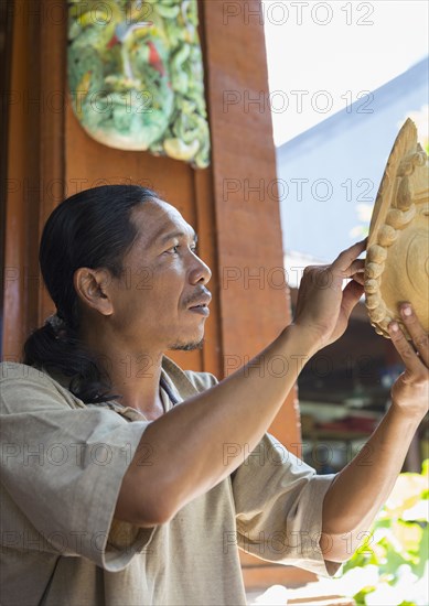 Wood worker examining piece in studio