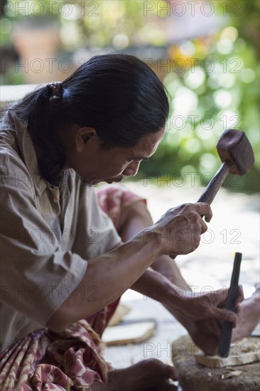 Wood worker chiseling piece in studio