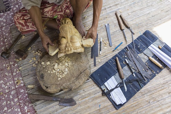 Craftsperson shaping wooden piece in studio