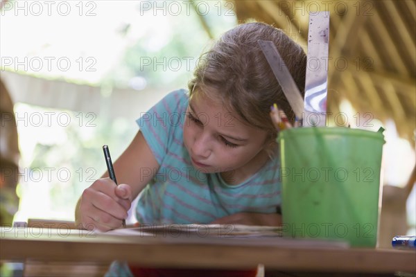 Caucasian girl writing at desk