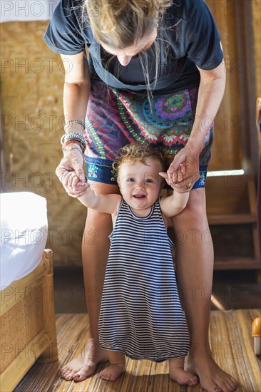 Caucasian mother helping baby stand