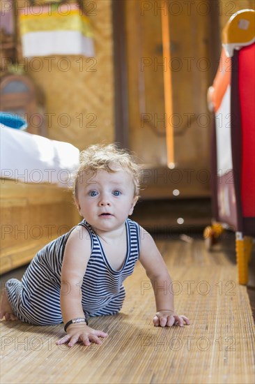 Caucasian baby crawling in bedroom