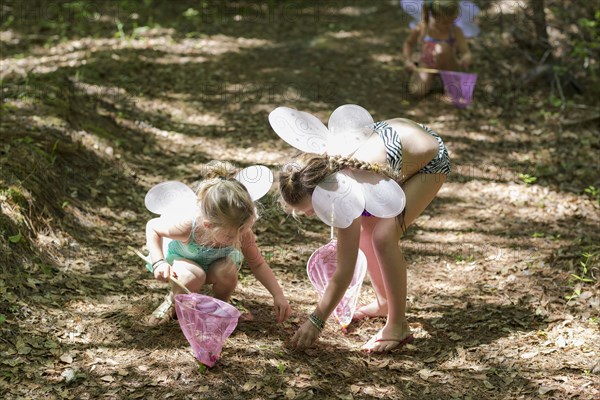 Caucasian girls playing dress up in forest