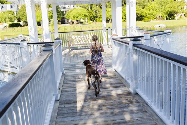 Caucasian girl walking with dog in gazebo