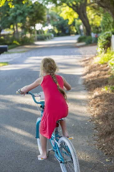 Caucasian girl riding bicycle on street