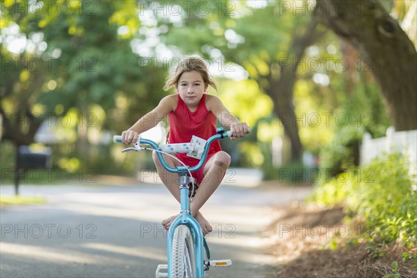 Caucasian girl riding bicycle on street