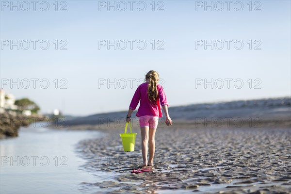Caucasian girl carrying bucket on beach