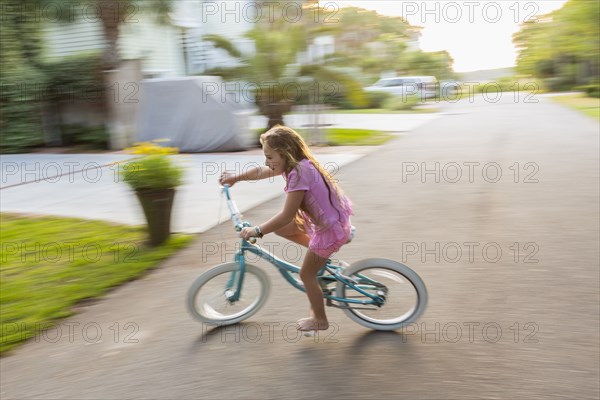 Caucasian girl riding bicycle on street