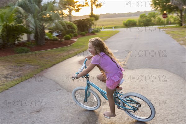 Caucasian girl riding bicycle on street