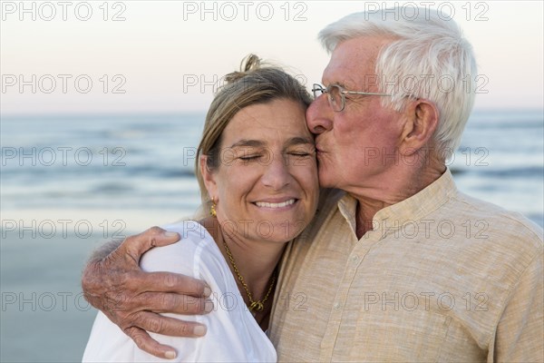 Caucasian father kissing daughter on beach