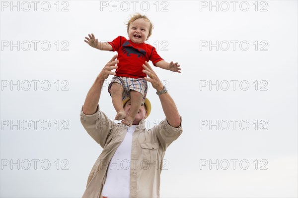 Caucasian man playing with grandson outdoors