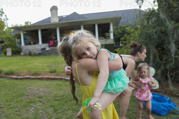 Girl carrying sister outdoors