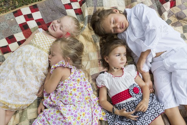 Caucasian children laying on blanket outdoors