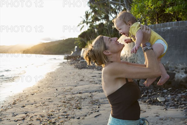 Caucasian mother holding baby on beach